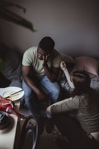 High angle view of female consoling male friend at home