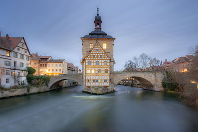 Arch bridge over river amidst buildings in city