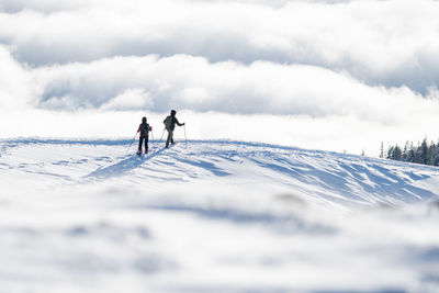 People on snowcapped mountain against sky