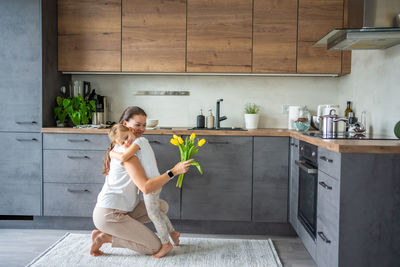 Full length of young woman standing in kitchen