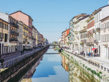 Canal amidst buildings against clear sky in city