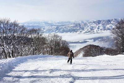 Rear view of man skiing on snow covered mountain against sky