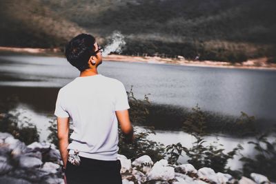 Rear view of man smoking at lake