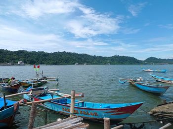 Boats moored in lake against blue sky