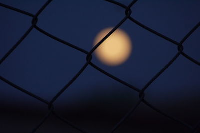 Full frame shot of chainlink fence against sky during sunset