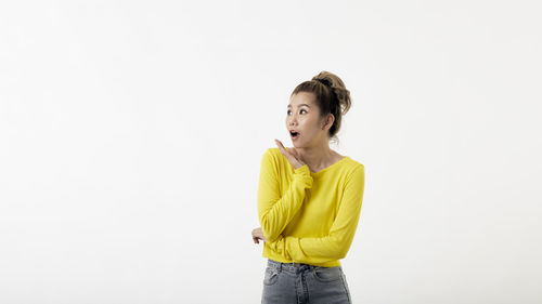 Portrait of young woman standing against white background