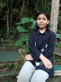 Portrait of young woman sitting on tree