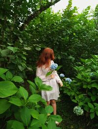 Redhead woman standing by flowering plants