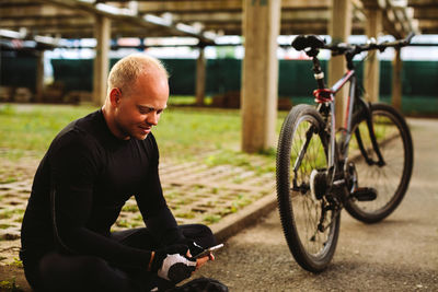 Side view of man bicycling against bicycle