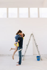 A young couple in love have moved into a new house and are making repairs painting white walls