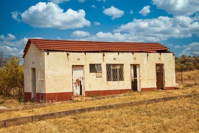 Exterior of abandoned house on field against sky