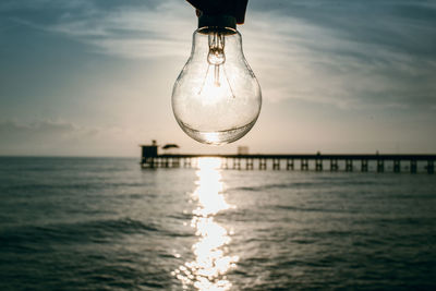 Reflection of illuminated light bulb on sea against sky
