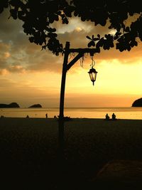 Silhouette people on beach against sky during sunset