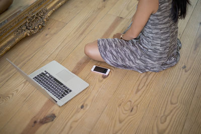 Young woman sitting on a wooden floor with her laptop