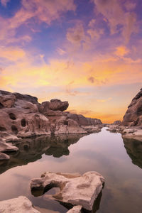 Rock formations by sea against sky during sunset