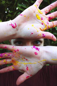 Close-up portrait of teenage girl showing paint of palms