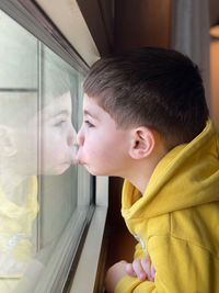 Side view of girl looking through window