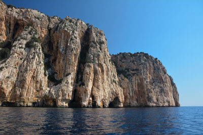 Rock formations in sea against clear sky