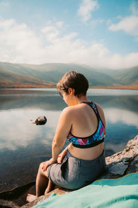 Young woman looking at lake against mountain range