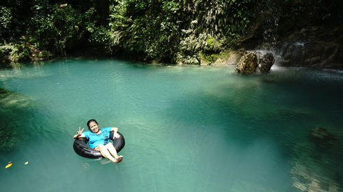 Portrait of woman relaxing in lake against trees