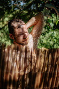 Man taking shower behind fence