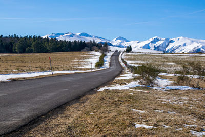 Road leading towards snowcapped mountains against sky