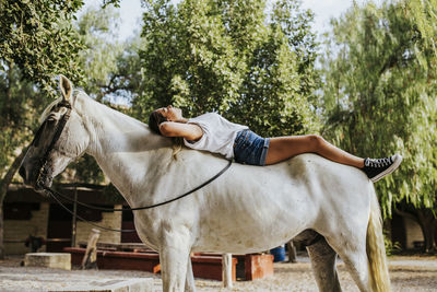 Beautiful young woman lying on top of white horse