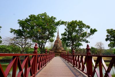 Footbridge amidst trees against clear sky