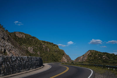 Road by mountains against blue sky