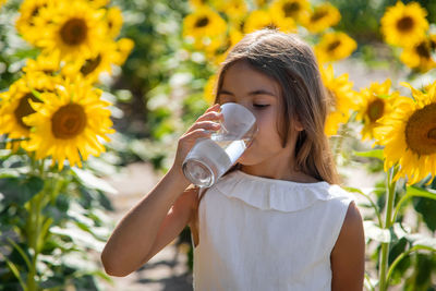 Cute girl drinking water at sunflower field