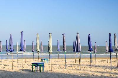 Closed canopies on beach against clear sky