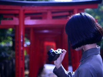 Side view of woman holding camera outdoors