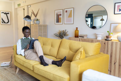 Happy woman using tablet pc on sofa in living room