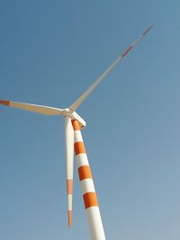 Low angle view of wind turbine against clear blue sky