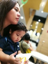 Mother with child sitting at illuminated restaurant