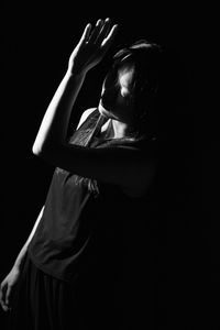 Rear view of woman standing against black background