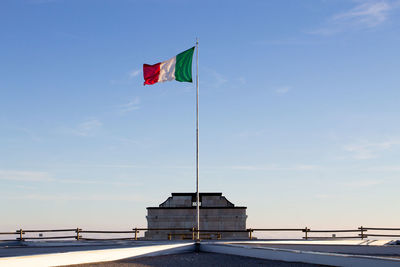 Flag by house against sky