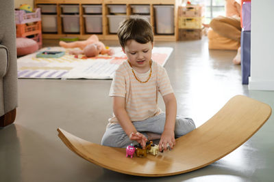 Child playing on balance board for toddlers in kids room. curvy rocker board used for motor physical