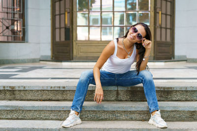 Casual style. stylish woman in sunglasses sitting on a stone staircase. she was