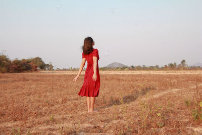 Woman standing on field against sky