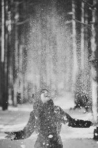 Happy young woman playing with snow in forest
