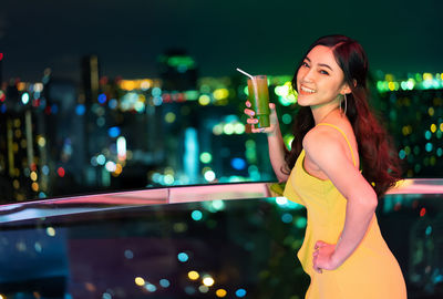 Young woman smiling while standing at night