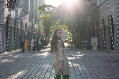 Woman standing on footpath in city