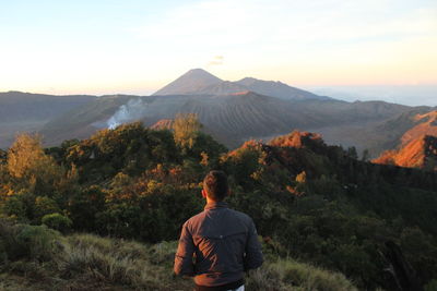 Rear view of woman looking at mountains against sky