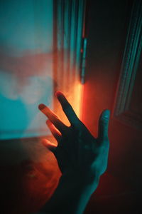 Close-up of person hand on illuminated window