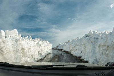 Wet road amidst icebergs against sky seen through windshield