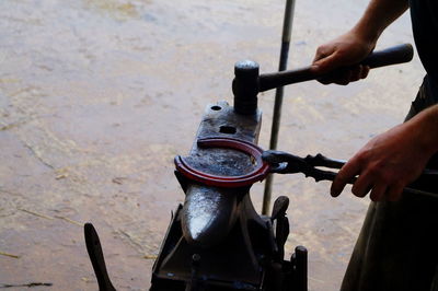 Cropped image of blacksmith hammering horseshoe on anvil