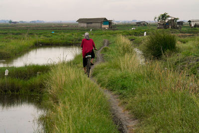 Rear view of woman walking on field