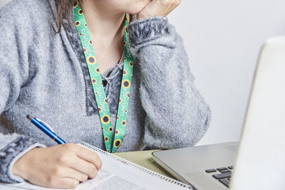 Midsection of woman writing in book on table