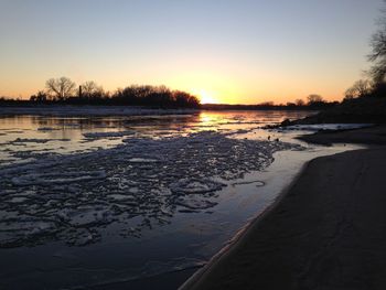 Scenic view of frozen lake against sky during sunset